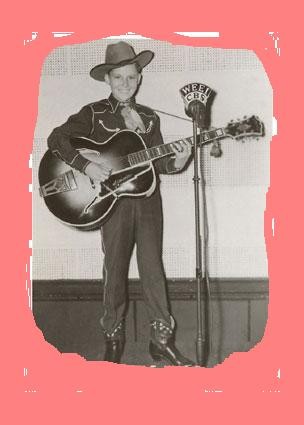 grayscale photo of small boy in cowboy hat playing guitar.