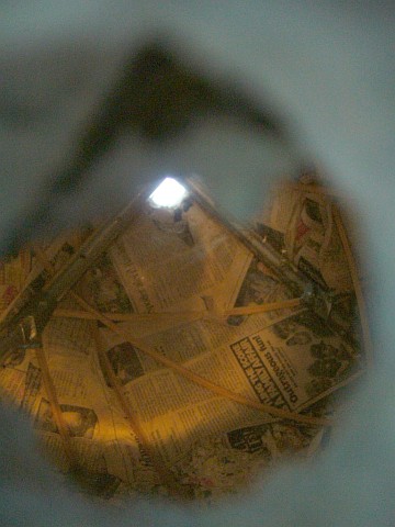 Looking through a hole into a hollow papier-mache sphere with steel and wooden ribs.